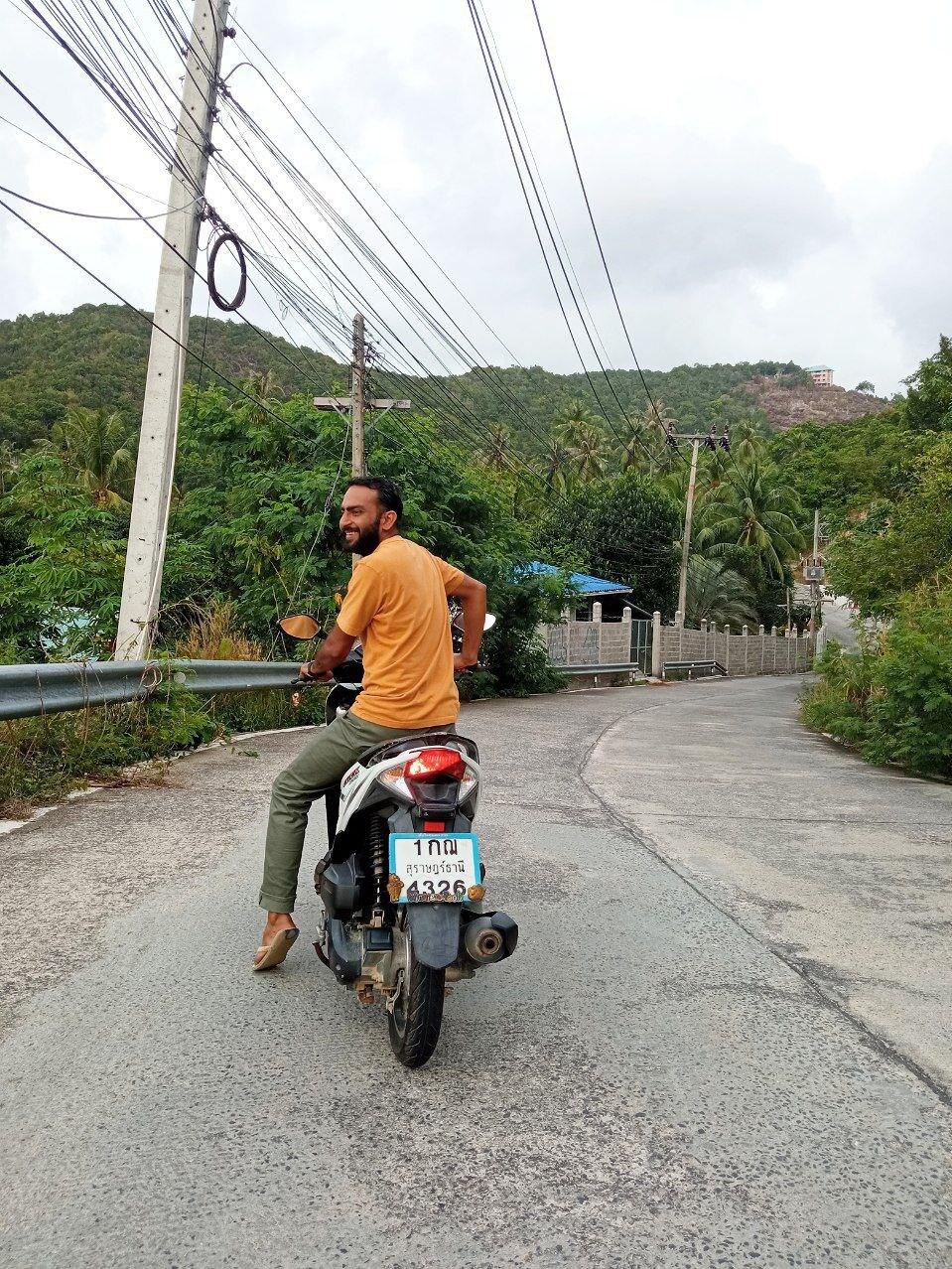 Nivesh on a scooter on a quiet tree-lined road